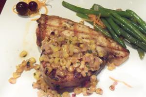 Grilled swordfish topped with corn relish and a side of green beans is served.  This delicious fish left a lasting impression.
