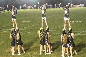 The womens varsity cheerleading team riles up the stands as the mens varsity football team plays against Annapolis Area Christian. Flyers, Gianna Langrehr (left), Emily Cassidy (middle), and Kaelyn Taylor (right), stand in a two legged extension while their bases hold them in the air.