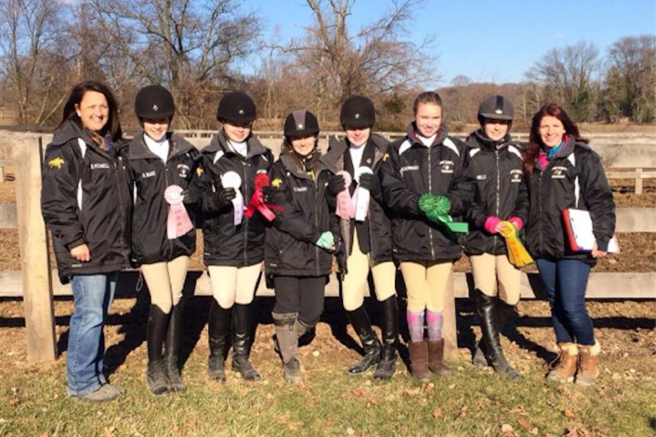 From left to right, head coach Dennise Petronelli poses with freshmen Brooke Hare, Mary Olsen, Taylor Crews, Alyssa Whitehead, Olivia Barnhart, captain Selina Petronelli, and her assistant coach Beth Hess with their ribbons after a show at Garrison Forest. Five members of the team qualified for regional due to the points they accumulated during the season.