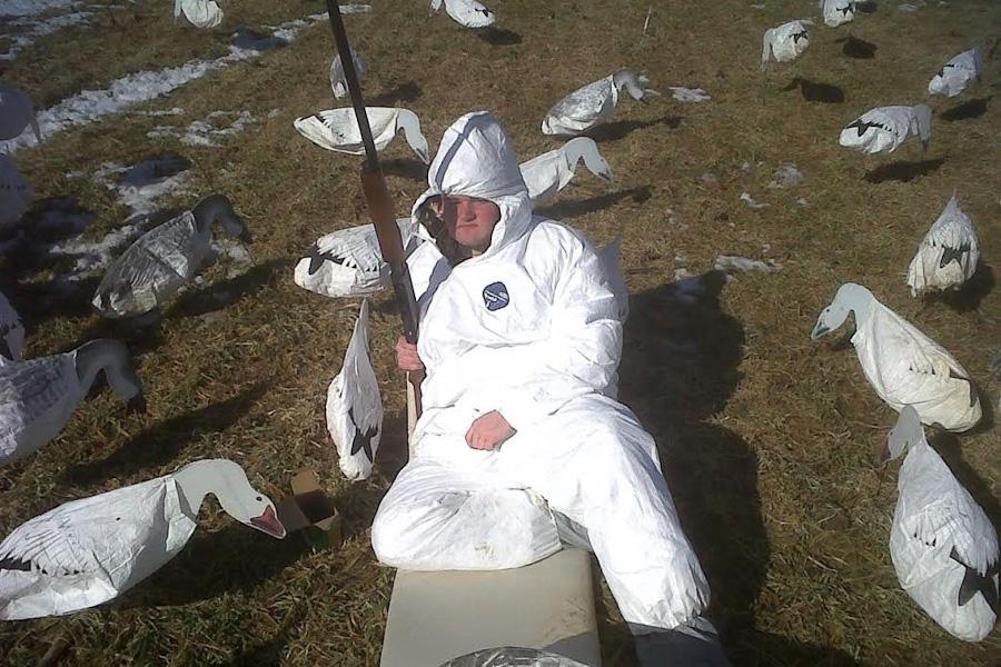 Opinion Editor Justin Hawkins poses for a picture during a break in the hunting. Hawkins is wearing a white suit to blend in the with the surrounding decoys.
