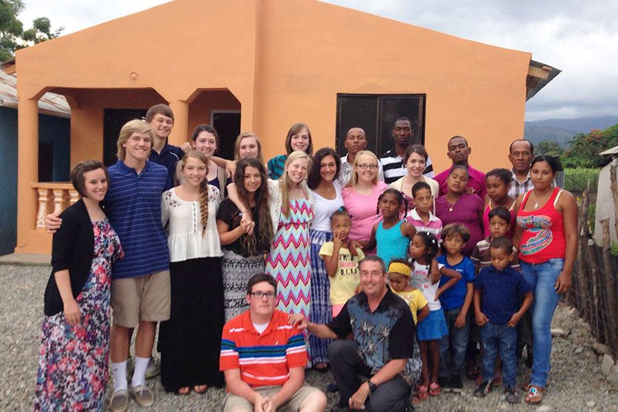 The JC Dominican Republic team stands with members of the San Juan community in front of Mary and Hubers finished house. The whole community came out that night to celebrate a house-warming party for the family.