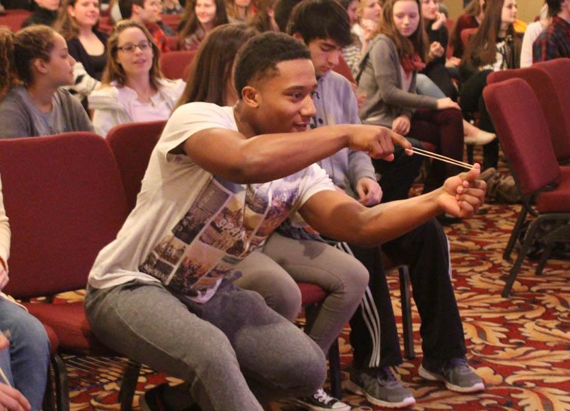 Senior Jerome Brown prepares to sling a rubber band to knock cups off of a table. Seniors played three different Minute to Win It-style games throughout the senior retreat.