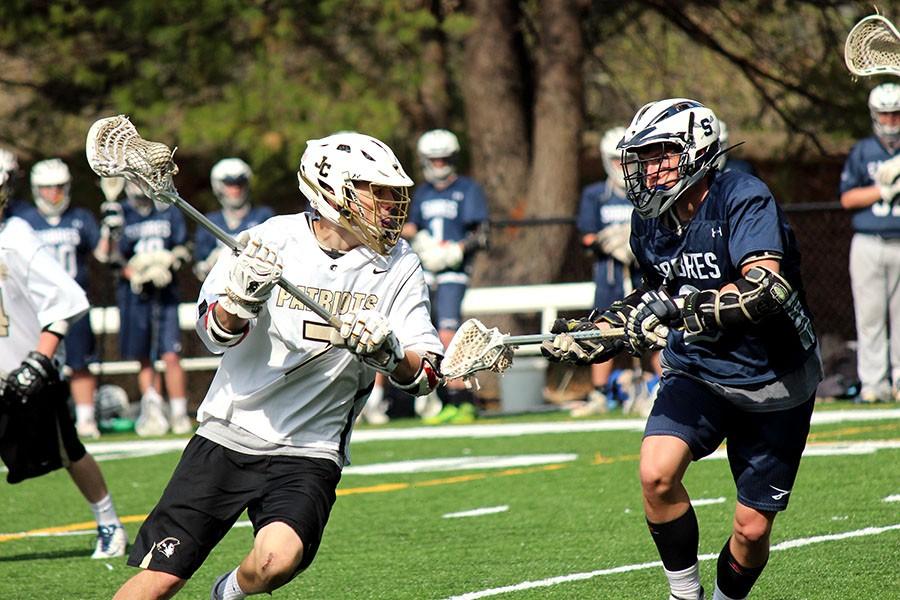 Driving in with the ball, junior and varsity midfielder Jimmy Schall races past the defender. Schall later shot and hit the right pipe. The team won 8-7 against St. Peter and Paul on Apr. 17 in one of their closest games of their championship season.