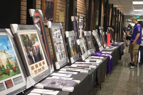 People view the items in the silent auction, which is supposed to raise money for JC, before the presentation starts. The silent auction contained autographed posters of local sports teams and memorabilia from the movie "Rudy". 
