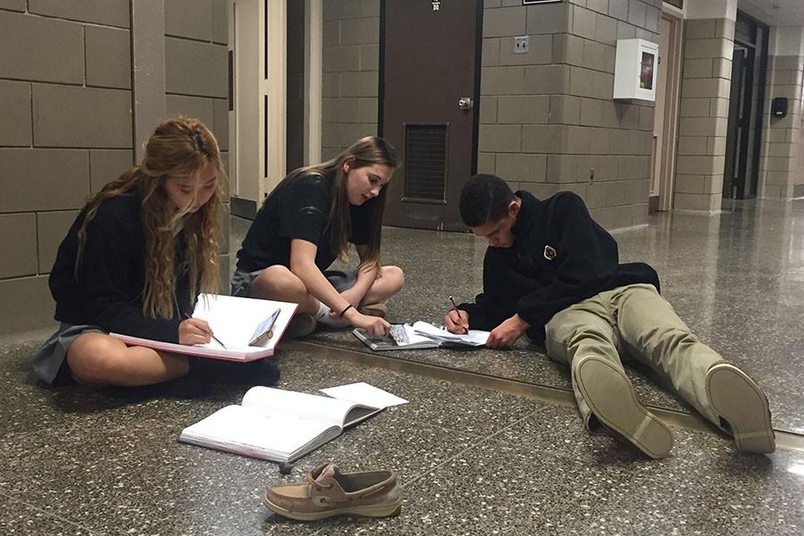 (Left to right) Juniors Yena Kim, Delaney Link, and CJ Beteta sit in the second floor hallway drawing what they see from that perspective. Students in their Studio 3 and 4 class were asked to draw something from a different perspective for a class project.  