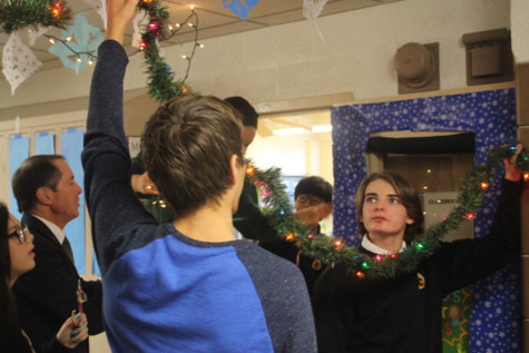 Hunter Peverley hangs decorations on the ceiling next to his advisory. The annual door decoration competition motivates students and faculty to put up extravagant hallway decorations. 