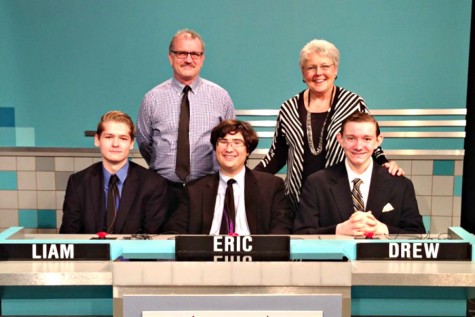 Senior Liam Dunn, Academic Team captain senior Eric Wright, and sophomore Drew Forthman (left to right) pose with academic team coach Robert Schick and Principal Madelyn Ball behind the Academic Team desk at the taping of Its Academic. The team beat New Town High School and Franklin High School in the Dec. 12 competition. 