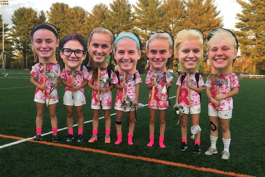 Seven women’s soccer seniors pose with their fatheads after their senior game against Mercy on Oct. 19. Women’s soccer is one of the varsity teams that emphasizes team unity on and off the field.