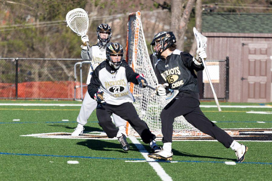 Sophomore defenseman Henri Marindin meets senior attackman Chris Tassanari at the goal line during drills in practice. The varsity lacrosse team is striving for a championship season to achieve the three-peat in the MIAA B Conference.