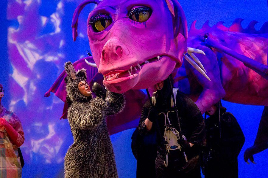 Senior Zachary Miller performing performing as Donkey, pets the puppet dragon during the final scene of Shrek The Musical. The productions dragon weighed about 80 lbs. and required six students to operate it.
