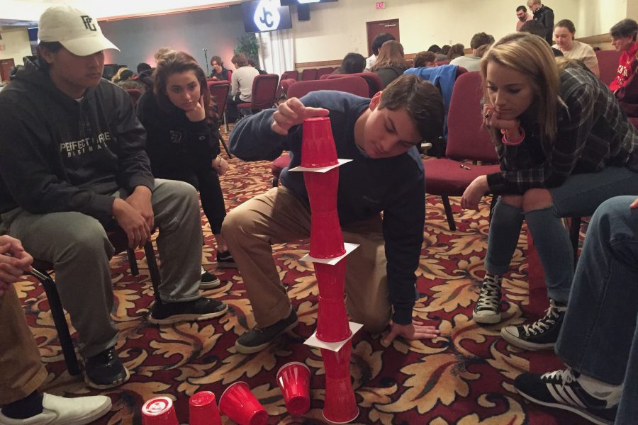 Senior Franco Caltabiano stacks cups as fellow seniors Tae Bogan, Maria Dunnock, and Shannon Norwood (left to right) watch during a small group activity on the Senior Retreat. The Senior Retreat took place on Monday, March 27, at Sandy Cove Ministries after being modified to not include the overnight portion of the retreat. 
