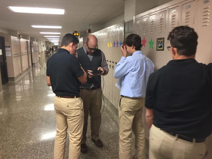 Physics teacher Anthony Davidson assists students with a physics experiment. This experiment used advanced technology in order to measure the acceleration and velocity of students as they walked at various paces.