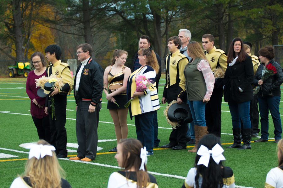 Senior marching band members Andrew Boeren, Megan Cleary, Reece Falter, Jonathan Kaufman, and Anna Kotula and their families stand on the football field at half time, waiting to be recognized. The band programs senior night was held Nov. 4, 2017. 