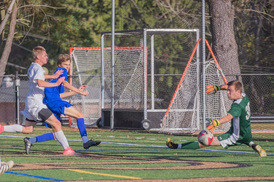 Senior Ben Florio makes a saves as senior David Pajerowski fights for the ball in a game against Loyola Blakefield on Wednesday, Oct. 25. The mens varsity soccer team lost 5-0.